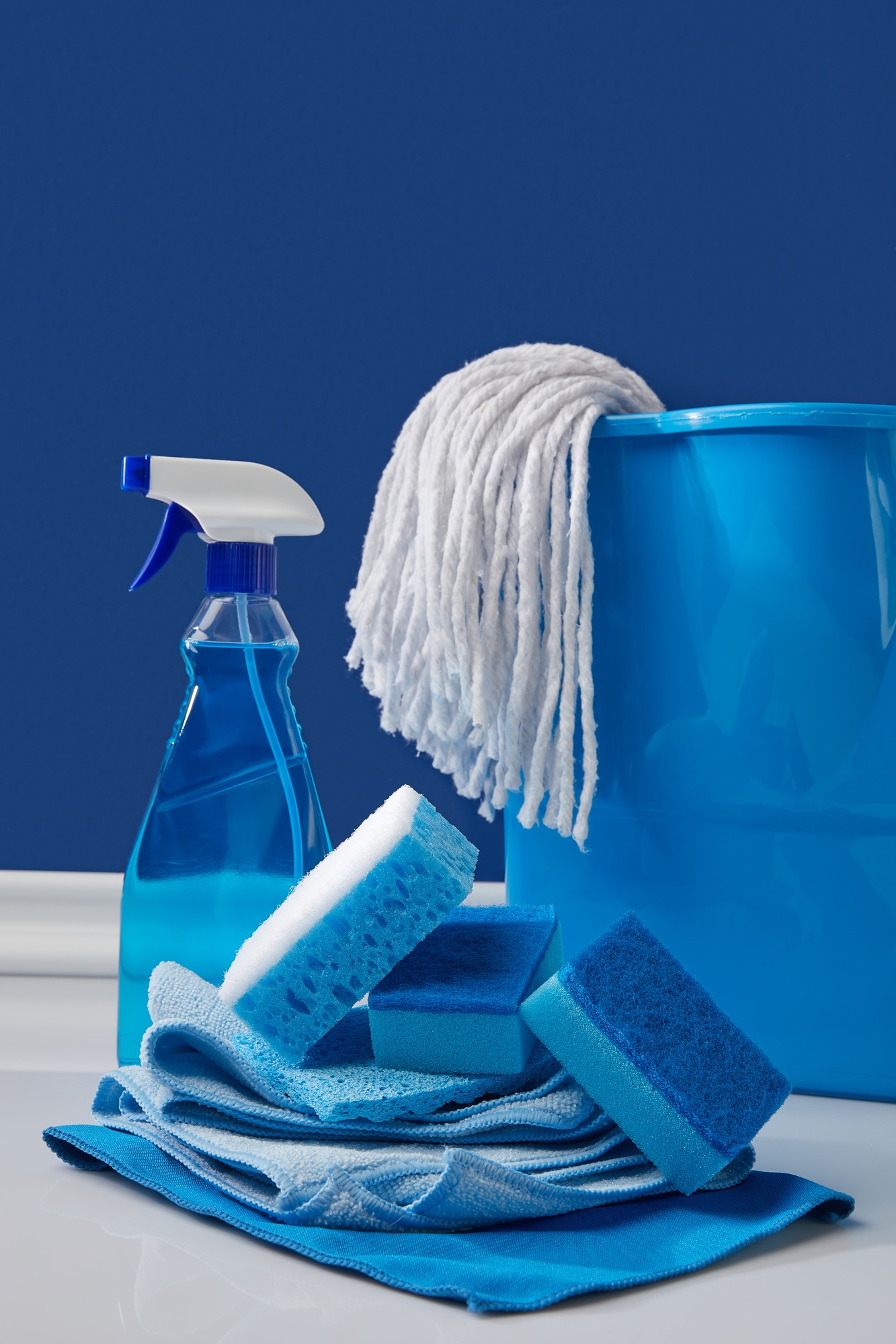 rags, bucket and spray for spring cleaning on blue